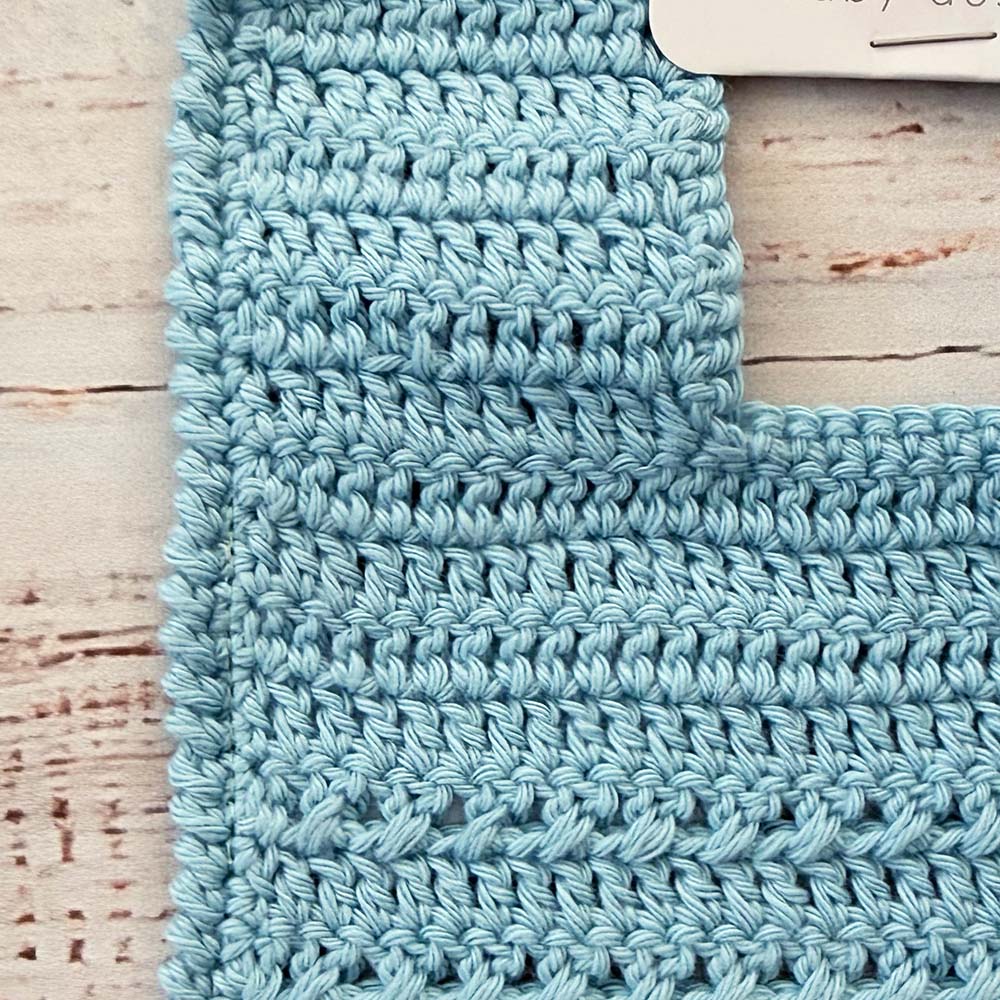 Babero de crochet celeste con tejido en relieve y patrón de punto