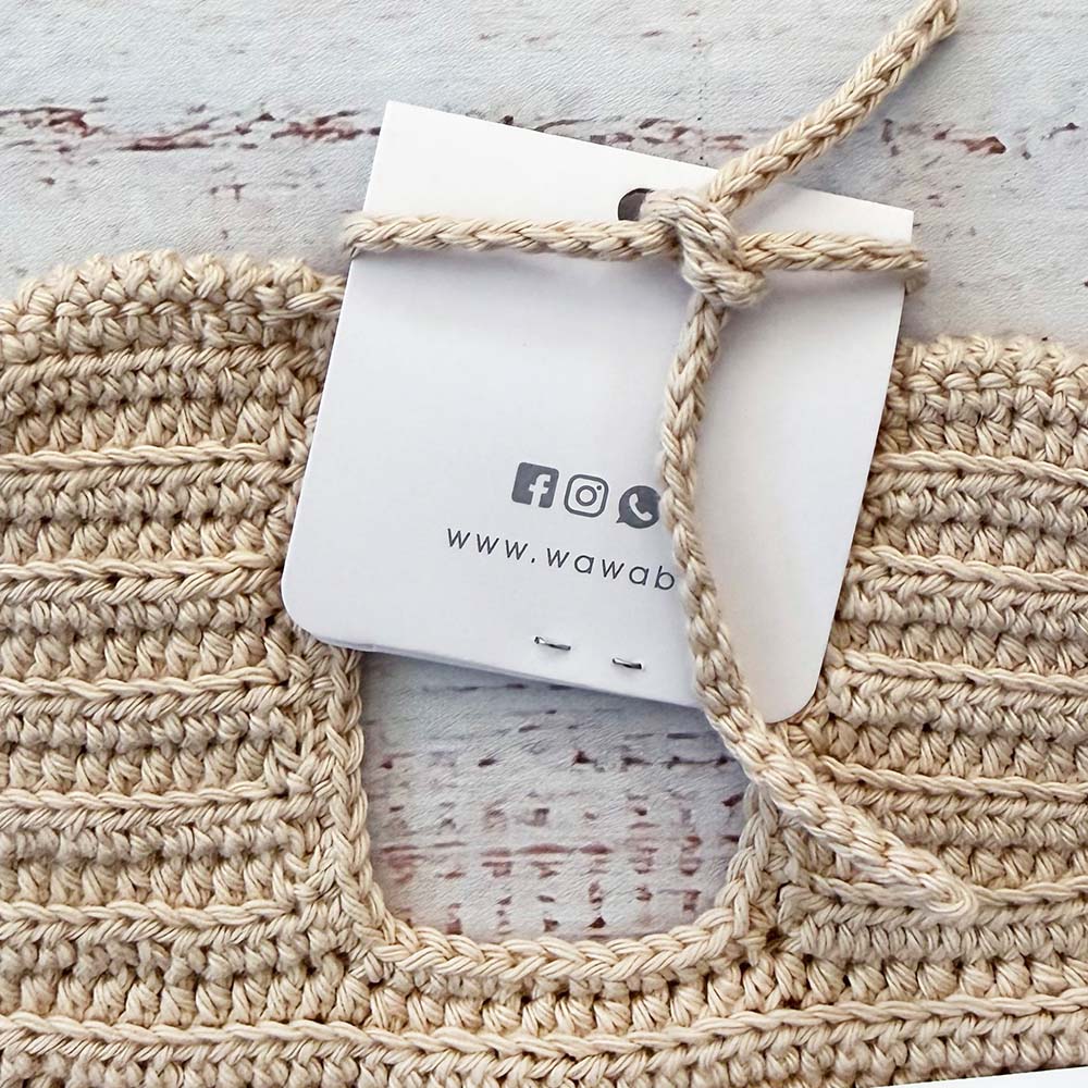 Babero de ganchillo beige con cinta superior para anudar y etiqueta colgante