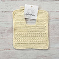 Babero de crochet color crema con bordes redondeados y asa para sujetar al cuello