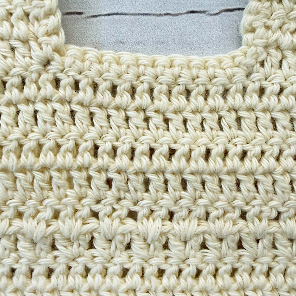 Babero de crochet crema con detalle de puntada tejida y borde enrollado