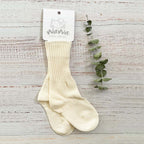 Calcetines de algodón beige para niño con canalé vertical y etiqueta colgante de marca.